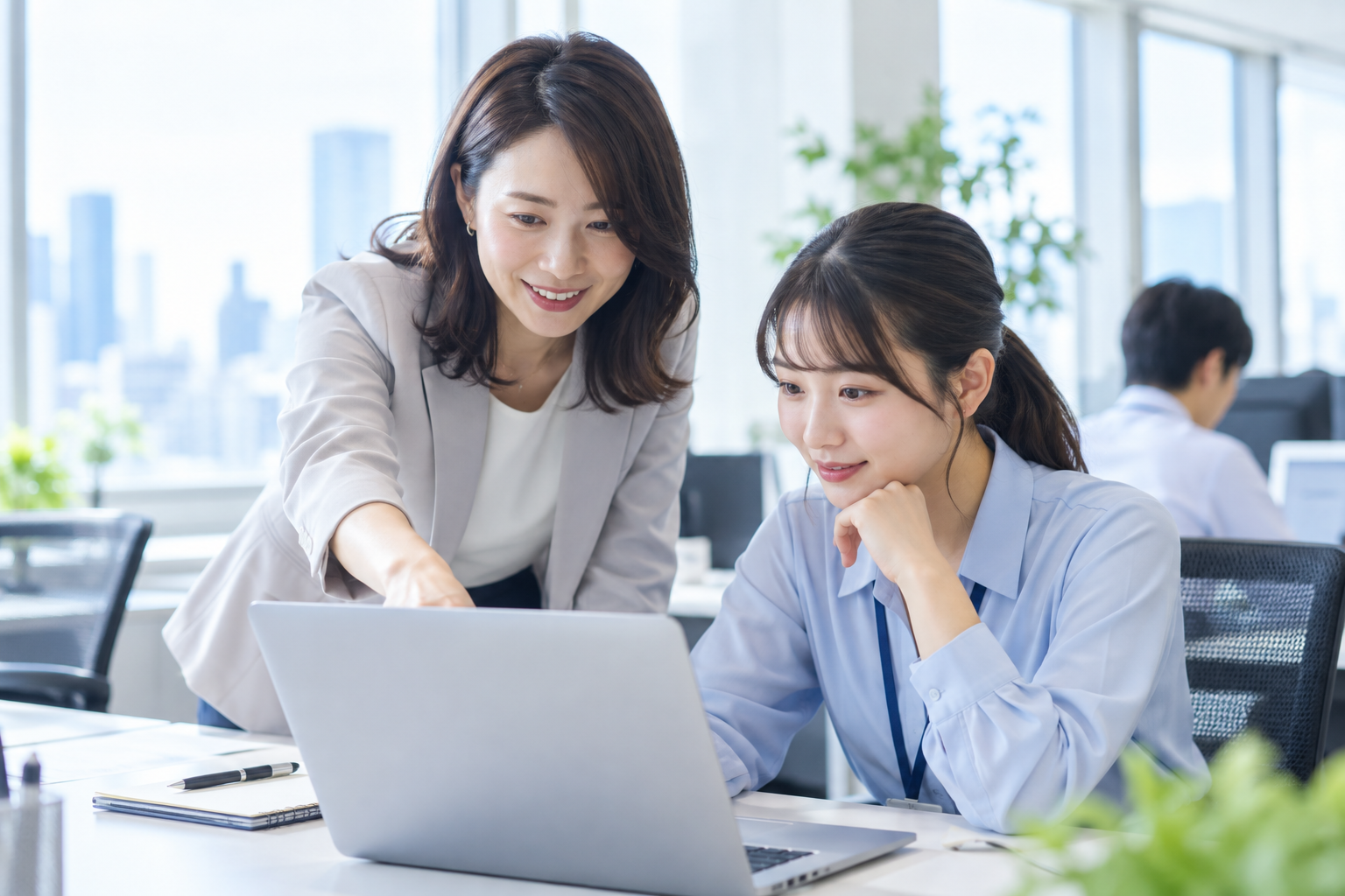 先輩スタッフが同僚に業務の進め方を教えている様子